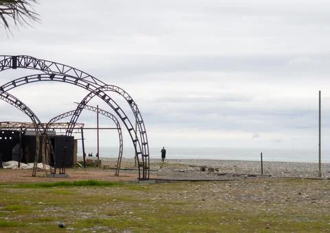 A man on the seashore next to an abandoned structure. Frame of rusty pieces o Stock Photos