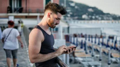 Man at the seaside using cell phone to type message Stock Photos
