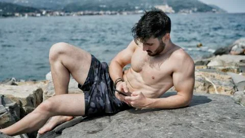 Man at the seaside using cell phone to type message Stock Photos