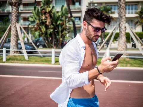 Man at the seaside using cell phone to type message Stock Photos