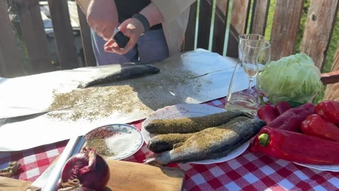 Man Seasoning Fresh Fish on Rustic Outdoor Table in Countryside 스톡 동영상 333523183