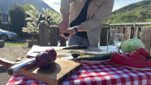 Man Seasoning Fresh Fish on Rustic Outdoor Table in Countryside Stock Footage 333523209