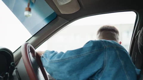 Man seated in car appears focused while preparing to reverse vehicle Stock Footage 327729369