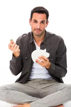 Man seated on the floor, looking at camera, putting a coin in a piggy bank Stock Photos
