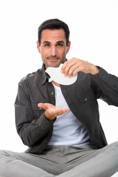Man seated on the floor, looking at camera and showing an empty piggy bank Stock Photos