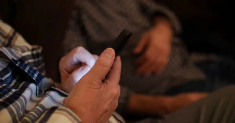 Man seated in the shadows using his mobile phone Stock Footage 152891496