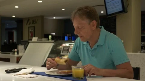 A man seating in cafeteria, eating and watching TV. Video stock 77174996