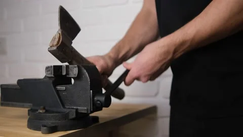 The man secured an old carving axe in a black vise with a screw handle, Close-up Stock Footage 148038558