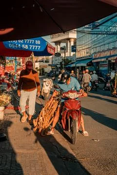 Man Secures Wooden Frame Load onto Red Scooter in Vietnam Stock-Fotos