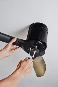 Man securing a ceiling fan while installing it Stock Photos