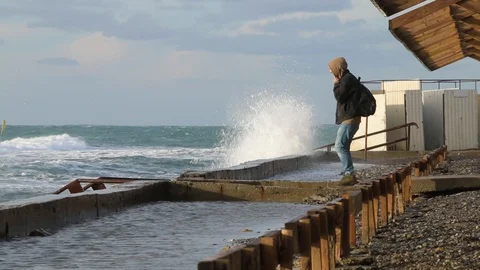 Man seeing at storm. Huge powerful waves breaking at seawall Stock Footage 99698660