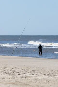 Man Seen from Behind Preparing His Fishing Rod in the Sea Stock Photos