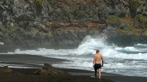 A man seen from behind walking on the seashore. Slow motion. Stock Footage 72622470