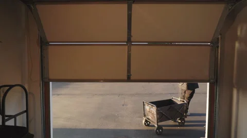 A man is seen with a cart in a garage during a peaceful morning scene with Vídeo Stock 307537872