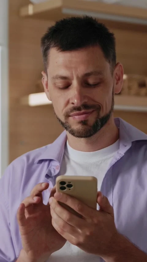 A man is seen engaging with his smartphone while in a casual and relaxed setting Stock Footage 314360376