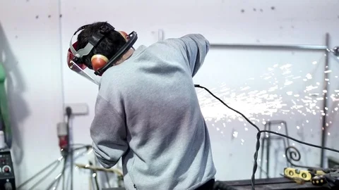 Man seen from his back working on metal while sparks fly Stock Footage 81859495