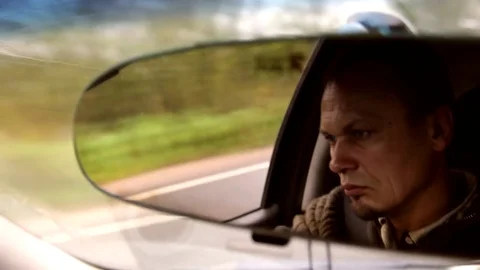 Man Seen In The Rearview Mirror Drives A Car Watching Around in the Countryside Video stock 70063629