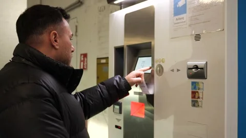 A man is seen from the side as he pays at a ticket machine in a parking garage Stock-Footage 329065717