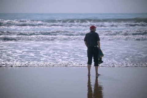 Man seen standing and looking at the ocean Stock Photos
