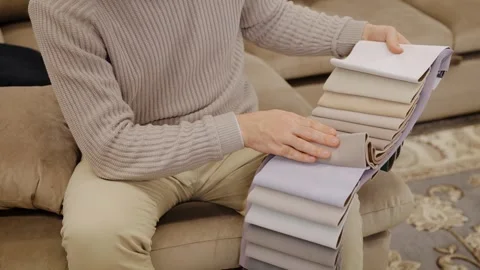 Man selecting fabric swatches for sofa upholstery, choosing textile samples Stock Footage 334654196