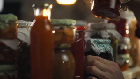 Man selecting jars of pickles in a well-stocked cellar full of preserved foo Stock Footage 331354886