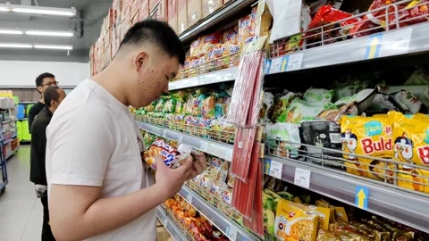 Man Selecting Snacks in Supermarket Store Aisle with Assorted Products Displayed Stock Footage 305367679