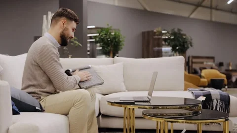 Man selecting sofa fabric samples, browsing options in modern furniture shop Stock Footage 334654249