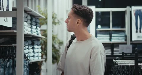 Man selecting stylish clothes for updated wardrobe, fashion reflecting current Stock Footage 312122588