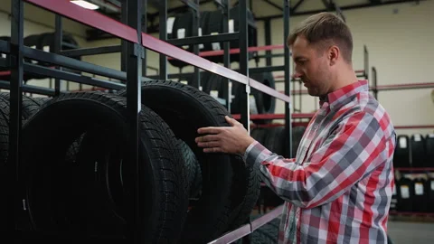 Man selecting a tire from the shelf in auto parts store Stock Footage 301551566