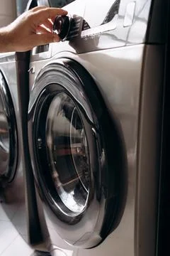 A man selects a program on an automatic washing machine to wash clothes at .. Foto stock