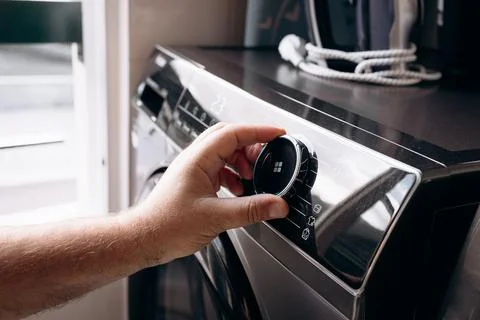 A man selects a program on an automatic washing machine to wash clothes at .. Stock Photos