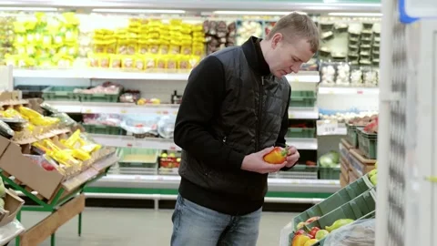 A man selects sweet peppers in a store. Customer wearing a black vest selects a Video stock 289001050