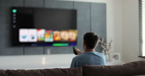 Man selects tv channels with remote control at living room on sofa. Young man Stock Footage 278532863
