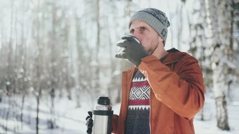 Man in self-isolation. A man drinking hot tea in winter forest. Relaxing aftter Stock Footage 128453798