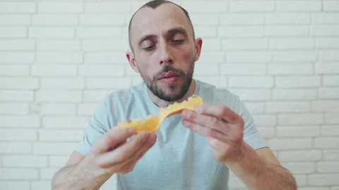 Man in self-isolation. A man eating orange. A man is sitting at home. Healthy Stock Footage 128436634