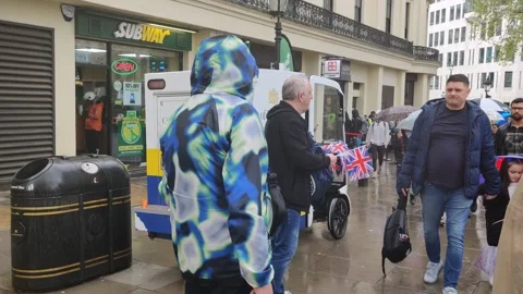 MAN SELLING FLAGS OUTSIDE KING CHARLES CORONATION 6 MAY 2023 4K Stock Footage 240493813