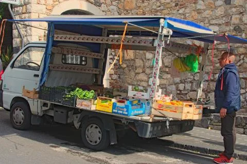 A man sells vegetables and fruits from a small truck. Stock Photos