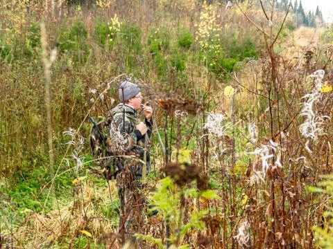 Man with semi-automatic weapons and backpack walks through mixed forest, hunt Stock Photos