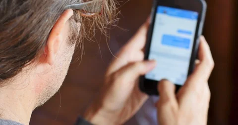 Man sending a message typing with his thumbs on his smart phone - OTS Video stock 93410240
