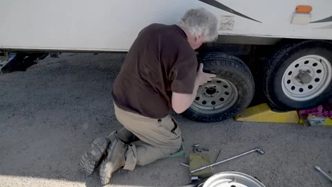 Man, senior changing wheel on trailer RV, 4k Stock Footage 274683648