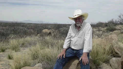 Man, senior, speaks to camera in desert, while seated Stock Footage 152179580