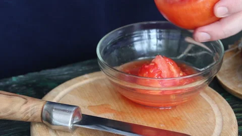 A man separates the pulp with a spoon from a cut tomato. Makes tomatoes stu.. Stock Footage 237590648