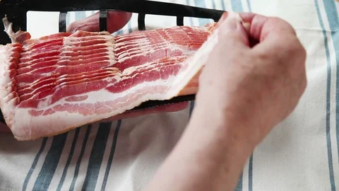 Man separates slice of raw bacon from pack Stock Footage 90187351