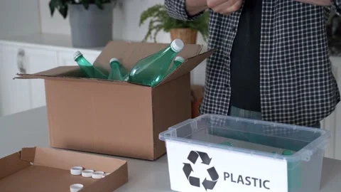 Man separates trash for recycling, puts plastic bottles into recycle box Stock Footage 196624288