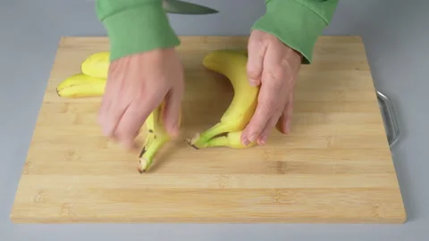 A man separates yellow bananas on a kitchen board close-up Stock Footage 232390156