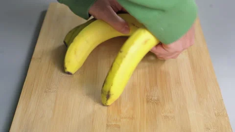 A man separates yellow bananas on a kitchen board close-up Stock Footage 232390741