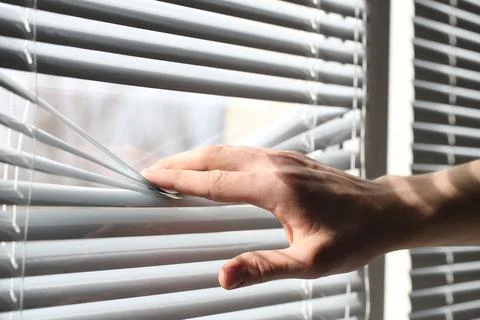Man separating slats of white blinds indoors, closeup Stock Photos