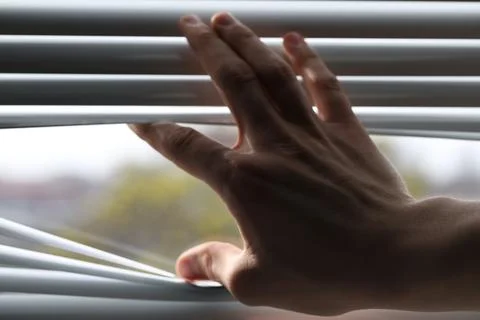 Man separating slats of white blinds indoors, closeup Stock Photos