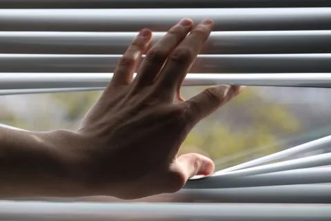 Man separating slats of white blinds indoors, closeup Fotos de archivo