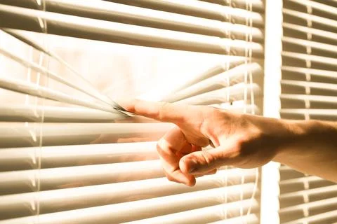 Man separating slats of white blinds indoors, closeup Fotos de archivo